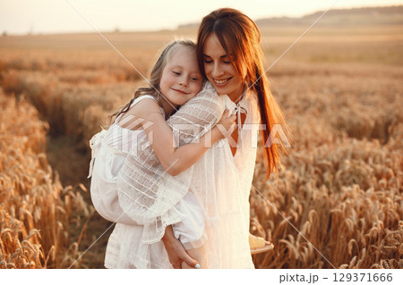Family in a summer field. Sensual photo. Cute little girl. Woman in a white dress. 129371666