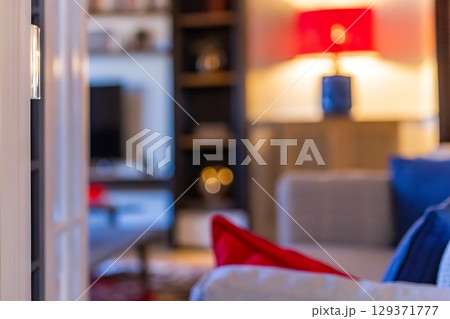 Cozy living room with stylish decor, warm lighting, and colorful cushions in soft focus 129371777
