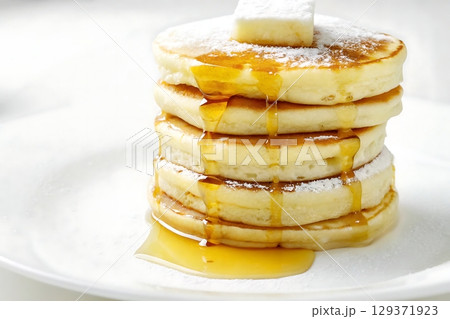 Fluffy Pancakes Stacked with Melting Butter and Drizzled Maple Syrup on White Plate 129371923
