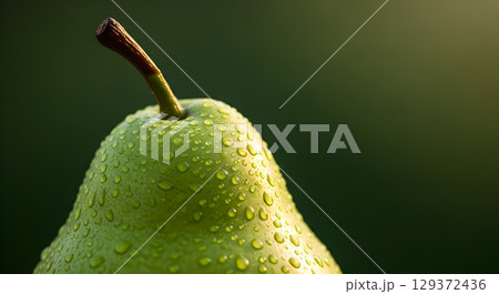 Fresh green pear with water droplets gleaming on its skin under soft lighting creating aesthetic 129372436