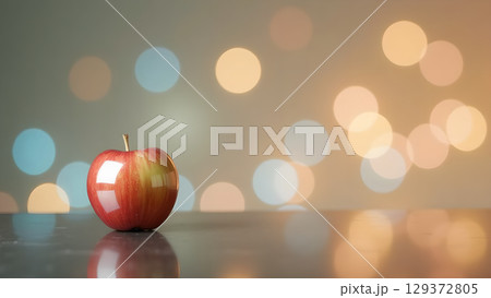 A vibrant red apple on a reflective surface amidst soft bokeh lights creating a festive ambience 129372805