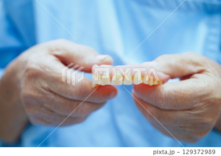 Asian senior woman patient holding teeth denture in her hand for chew food. Asian senior woman patient holding teeth denture in her hand for chew food. 129372989