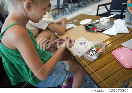 Mother and her daughter paint Halloween cookies  129373502