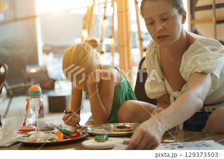 Mother and her daughter paint Halloween cookies  129373503