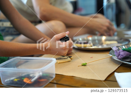 Mother and her daughter paint Halloween cookies Mother and her daughter paint Halloween cookies 129373515