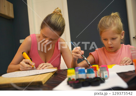 A mother and her young daughter engage in a colorful painting activity A mother and her young daughter engage in a colorful painting activity 129373542