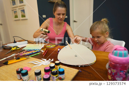 A mother and her young daughter engage in a colorful painting activity  129373574