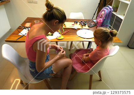 A mother and her young daughter engage in a colorful painting activity A mother and her young daughter engage in a colorful painting activity 129373575