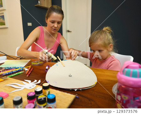 A mother and her young daughter engage in a colorful painting activity  129373576