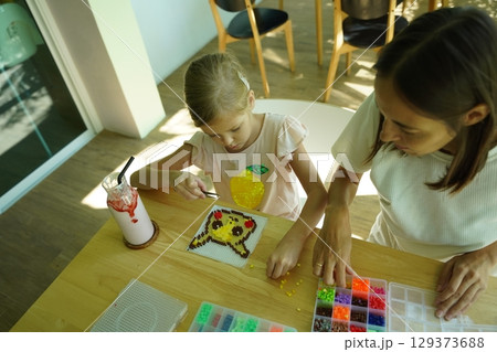 Teacher in workshop teched two girls how to assemble a thermo mosaic Teacher in workshop teched two girls how to assemble a thermo mosaic 129373688