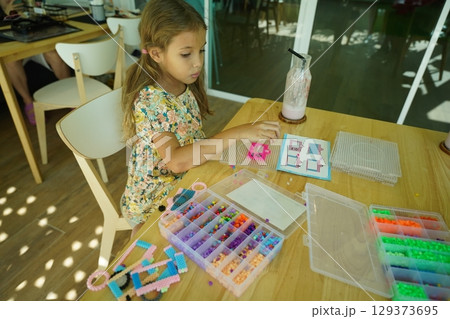 Teacher in workshop teched two girls how to assemble a thermo mosaic Teacher in workshop teched two girls how to assemble a thermo mosaic 129373695