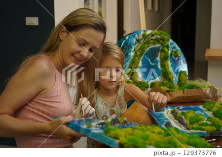 A mother and her daughter craft vibrant natural landscapes  129373776