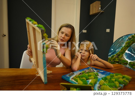 A mother and her daughter craft vibrant natural landscapes  129373778