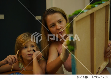 A mother and her daughter craft vibrant natural landscapes  129373780