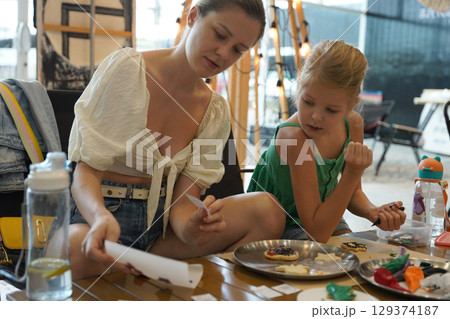 Mother and her daughter paint Halloween cookies  Mother and her daughter paint Halloween cookies  129374187