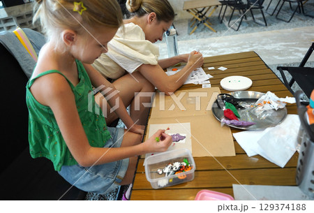 Mother and her daughter paint Halloween cookies  Mother and her daughter paint Halloween cookies  129374188