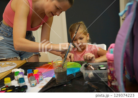 A mother and her young daughter engage in a colorful painting activity  129374223