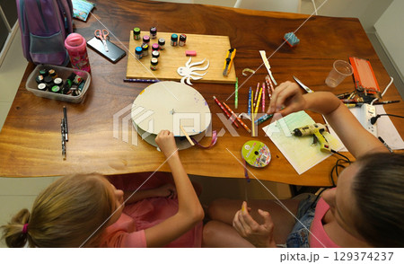 A mother and her young daughter engage in a colorful painting activity  129374237