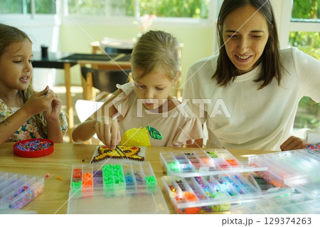 Teacher in workshop teched two girls how to assemble a thermo mosaic  129374263