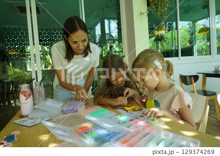 Teacher in workshop teched two girls how to assemble a thermo mosaic  129374269