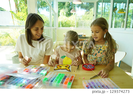 Teacher in workshop teched two girls how to assemble a thermo mosaic Teacher in workshop teched two girls how to assemble a thermo mosaic 129374273