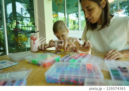 Teacher in workshop teched two girls how to assemble a thermo mosaic Teacher in workshop teched two girls how to assemble a thermo mosaic 129374361