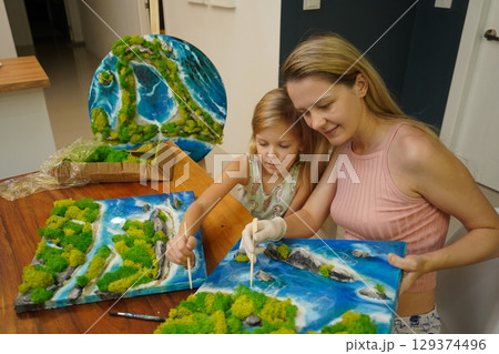 A mother and her daughter craft vibrant natural landscapes  129374496