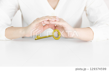 Hands Protecting Golden Key Symbolizing Opportunity and Security 129374599