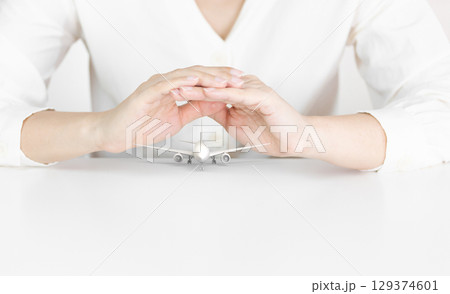 Hands Protecting White Airplane Model Symbolizing Travel Safety Hands Protecting White Airplane Model Symbolizing Travel Safety 129374601