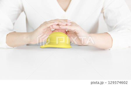 Protective Hands Above Yellow Hard Hat Representing Workplace Safety Protective Hands Above Yellow Hard Hat Representing Workplace Safety 129374602