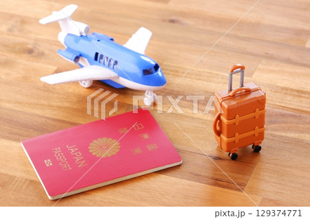 日本のパスポート（一般旅券10年用赤色）と飛行機、スーツケースで、海外旅行のイメージ 129374771