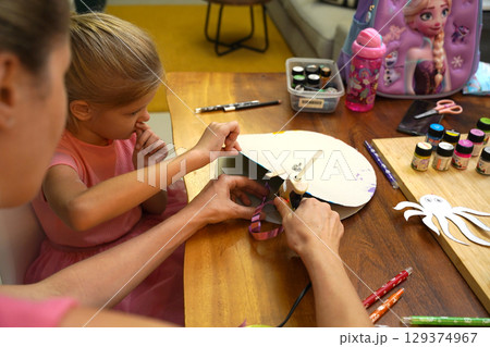 A mother and her young daughter engage in a colorful painting activity  129374967