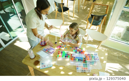 Teacher in workshop teched two girls how to assemble a thermo mosaic Teacher in workshop teched two girls how to assemble a thermo mosaic 129375040