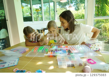 Teacher in workshop teched two girls how to assemble a thermo mosaic  129375083