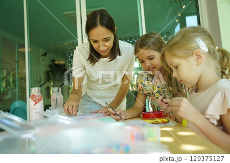 Teacher in workshop teched two girls how to assemble a thermo mosaic Teacher in workshop teched two girls how to assemble a thermo mosaic 129375127