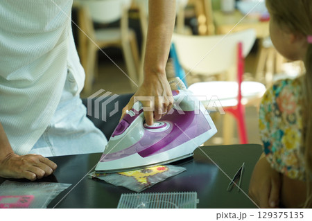 Teacher in workshop teched two girls how to assemble a thermo mosaic  129375135