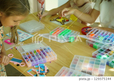 Teacher in workshop teched two girls how to assemble a thermo mosaic Teacher in workshop teched two girls how to assemble a thermo mosaic 129375144