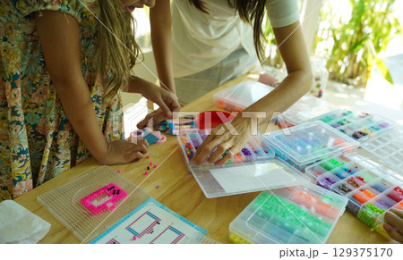 Teacher in workshop teched two girls how to assemble a thermo mosaic  129375170
