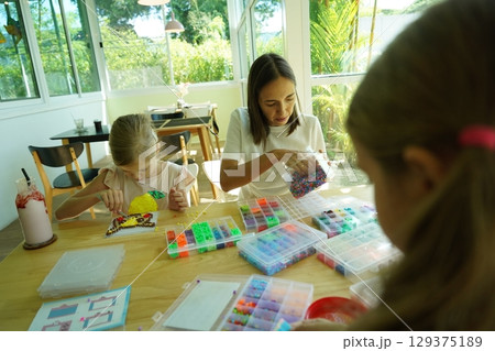 Teacher in workshop teched two girls how to assemble a thermo mosaic  129375189