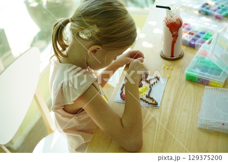 Teacher in workshop teched two girls how to assemble a thermo mosaic  129375200