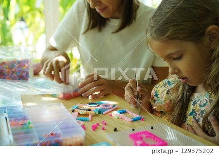 Teacher in workshop teched two girls how to assemble a thermo mosaic  129375202