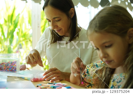 Teacher in workshop teched two girls how to assemble a thermo mosaic  129375204