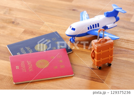 日本のパスポート（5年用と10年用）と飛行機、スーツケースで、海外旅行のイメージ 129375236