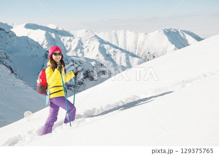 Solo Female Climber Ascends Snowy Mountain Peak Under Clear Winter Skies 129375765