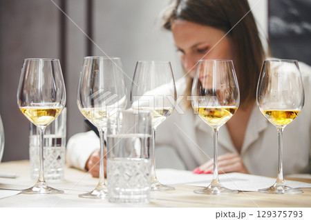 Female sommelier tasting wine during training wine school. Alcoholic beverages degustation courses. Winemaking school, wine waiter certification. 129375793