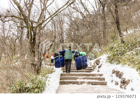 Porter workers carrying construction materials along steep steps at Huangshan or Yellow Mountain. 129376071