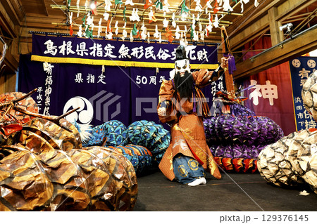石見神楽 (夜神楽) 神社拝殿舞台で蜷局を巻く大蛇を退治しようとしている主人公の演者 129376145