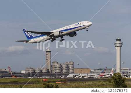 管制塔をバックに離陸する飛行機 129376572