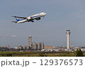 管制塔をバックに離陸する飛行機 129376573