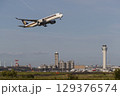 管制塔をバックに離陸する飛行機 129376574